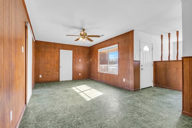 interior space featuring ceiling fan and wood walls