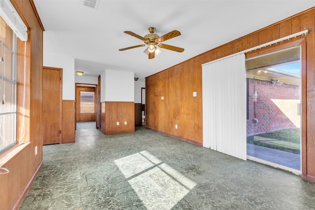 empty room with ceiling fan and wooden walls