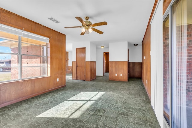 spare room featuring ceiling fan and wood walls