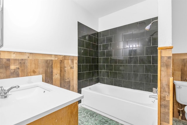 full bathroom featuring toilet, tiled shower / bath, vanity, and wooden walls