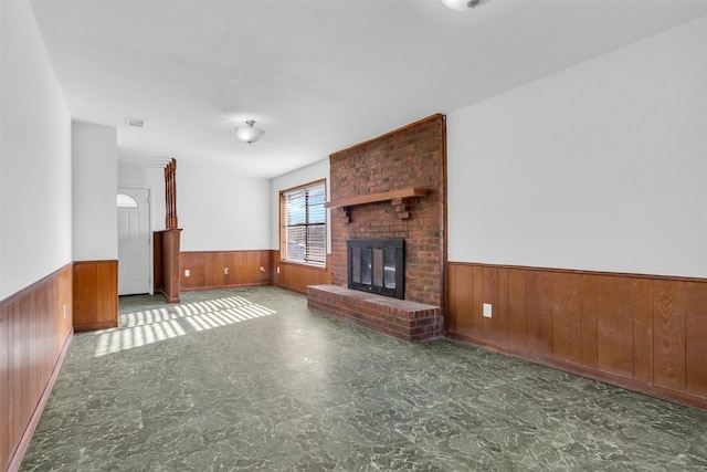 unfurnished living room with a brick fireplace and wooden walls