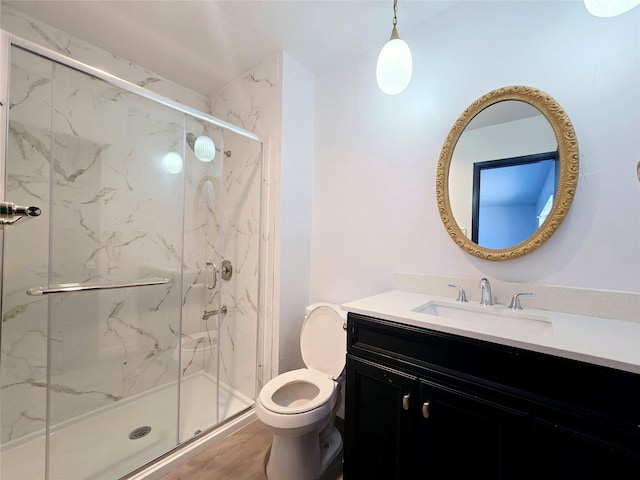 bathroom with hardwood / wood-style floors, toilet, a shower with door, and vanity