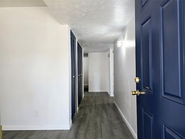 hallway with dark hardwood / wood-style flooring and a textured ceiling