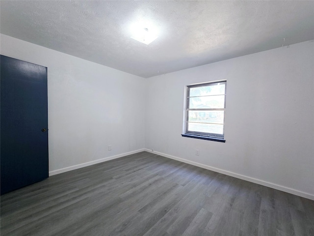 spare room featuring a textured ceiling and dark hardwood / wood-style flooring