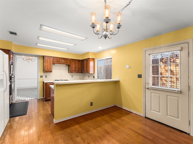 kitchen featuring kitchen peninsula, stainless steel oven, wood-type flooring, hanging light fixtures, and a chandelier