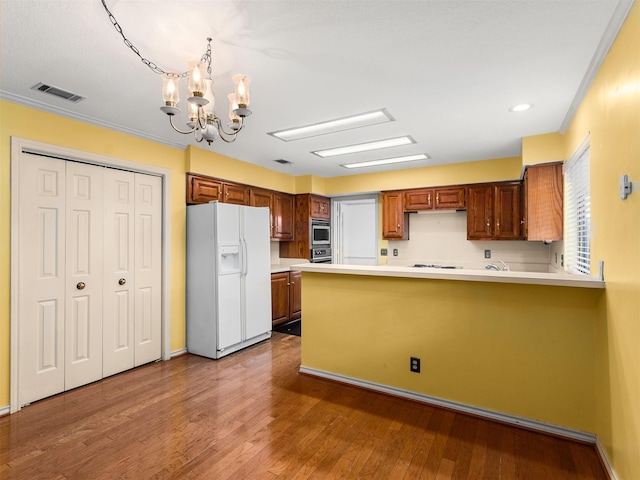 kitchen featuring decorative light fixtures, a notable chandelier, hardwood / wood-style floors, kitchen peninsula, and white fridge with ice dispenser