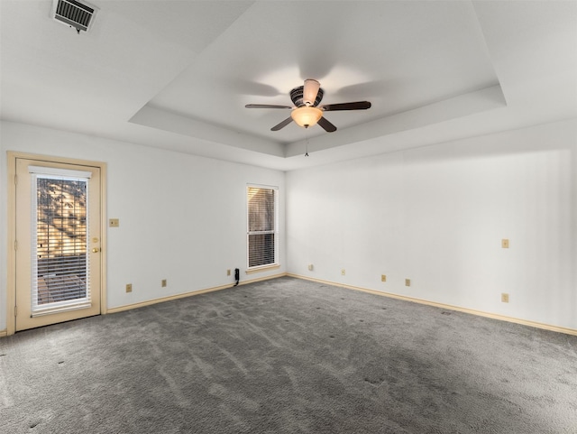 carpeted spare room featuring ceiling fan and a tray ceiling