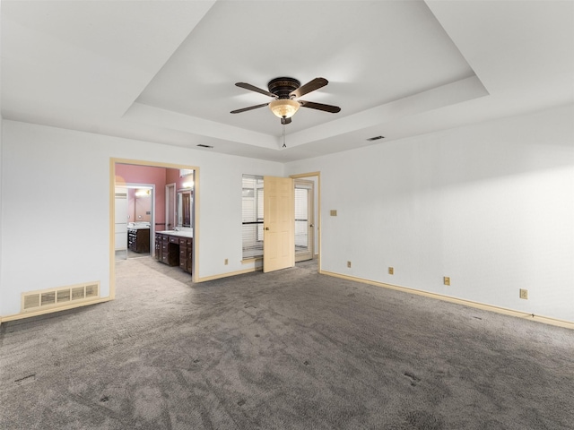 carpeted empty room featuring ceiling fan and a tray ceiling