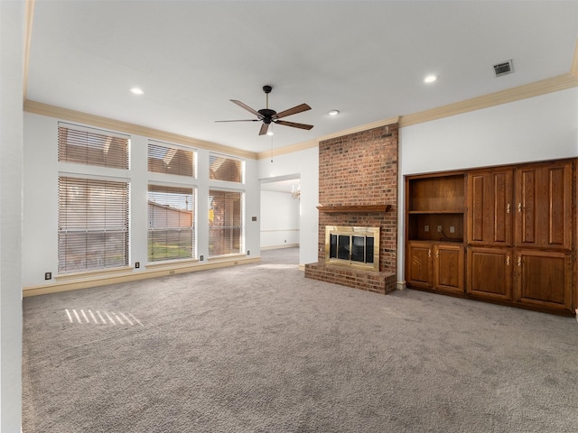 unfurnished living room featuring a brick fireplace, ornamental molding, ceiling fan, and carpet flooring