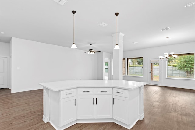 kitchen featuring hardwood / wood-style flooring, a kitchen island, pendant lighting, ceiling fan with notable chandelier, and white cabinets