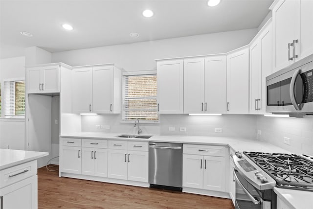 kitchen with sink, white cabinetry, backsplash, and stainless steel appliances