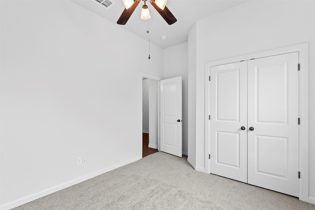 unfurnished bedroom featuring ceiling fan, light colored carpet, and a closet