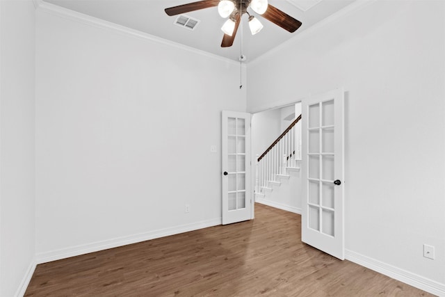 empty room with ceiling fan, hardwood / wood-style floors, crown molding, and french doors