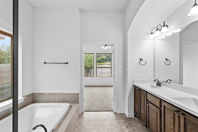 bathroom featuring ceiling fan, vanity, tile patterned floors, and a relaxing tiled tub