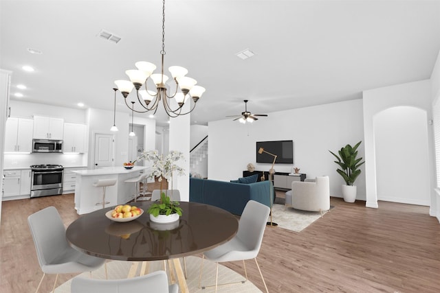 dining room with ceiling fan with notable chandelier and light hardwood / wood-style flooring