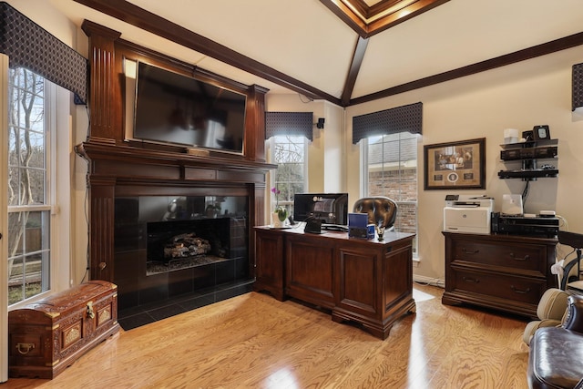 office featuring light hardwood / wood-style flooring, a tiled fireplace, and vaulted ceiling with beams