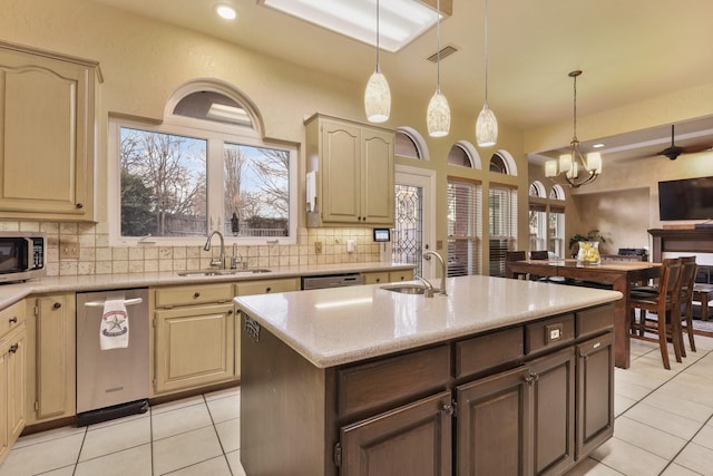 kitchen featuring backsplash, a notable chandelier, a center island with sink, sink, and appliances with stainless steel finishes