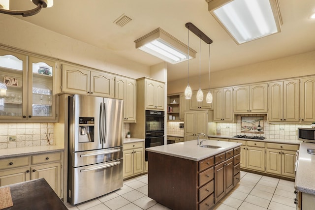 kitchen with decorative light fixtures, stainless steel appliances, sink, light tile patterned flooring, and a center island with sink