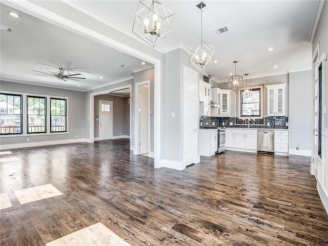 kitchen with decorative light fixtures, tasteful backsplash, appliances with stainless steel finishes, white cabinets, and ceiling fan with notable chandelier