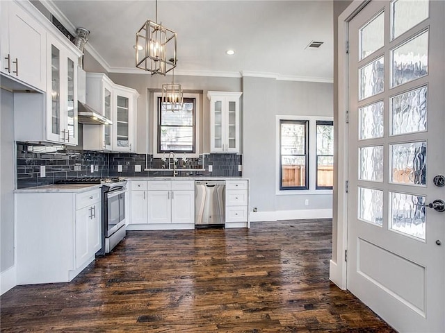 kitchen with white cabinets, appliances with stainless steel finishes, decorative light fixtures, dark hardwood / wood-style floors, and crown molding