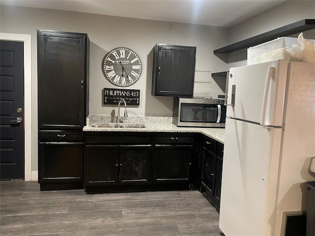 kitchen featuring light stone countertops, white refrigerator, and sink