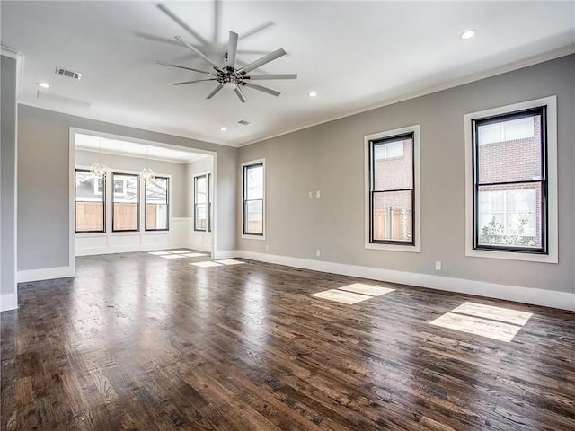 empty room featuring ceiling fan with notable chandelier, dark wood-type flooring, and crown molding