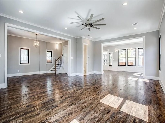 unfurnished living room featuring ceiling fan with notable chandelier, a wealth of natural light, dark hardwood / wood-style floors, and crown molding