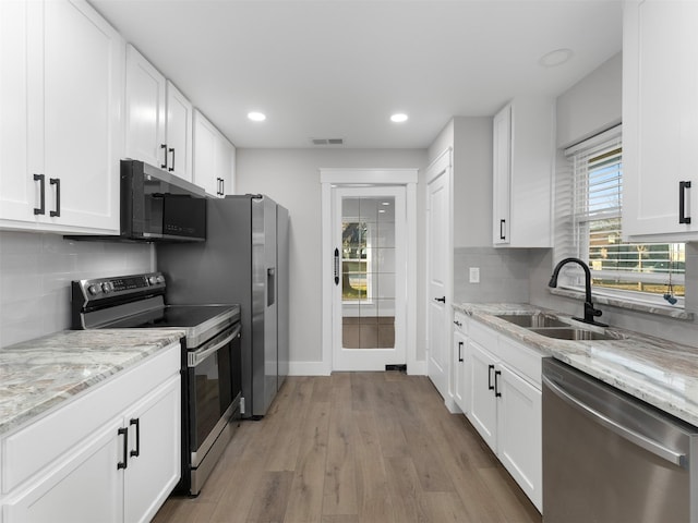 kitchen with backsplash, sink, stainless steel appliances, white cabinets, and light stone counters