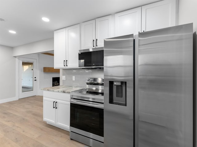 kitchen with light stone counters, light hardwood / wood-style floors, white cabinetry, and appliances with stainless steel finishes