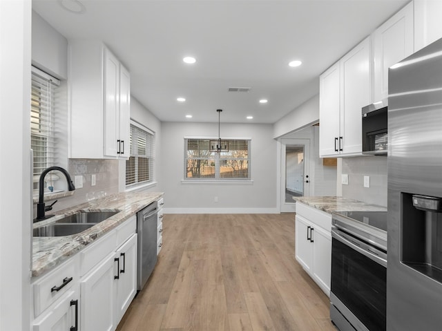 kitchen featuring light stone countertops, appliances with stainless steel finishes, white cabinetry, and sink