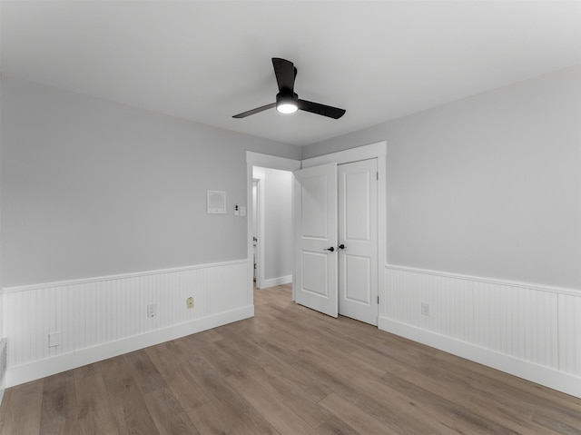 unfurnished bedroom featuring ceiling fan, light hardwood / wood-style floors, and a closet