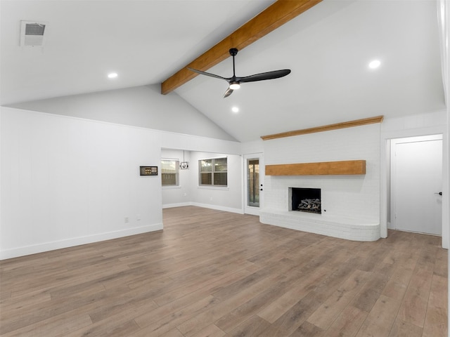 unfurnished living room featuring ceiling fan, a large fireplace, beam ceiling, and hardwood / wood-style floors