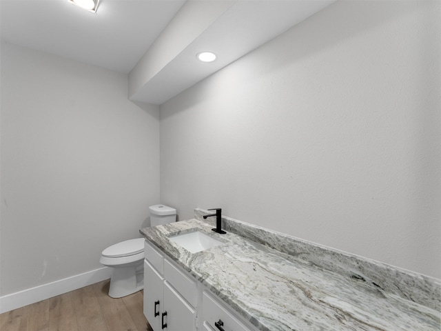 bathroom with hardwood / wood-style flooring, toilet, and vanity