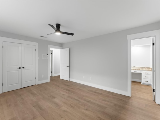 unfurnished bedroom featuring ceiling fan, ensuite bath, light hardwood / wood-style flooring, and a closet