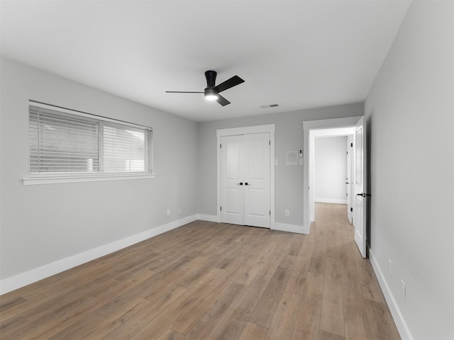 unfurnished bedroom with light wood-type flooring, ceiling fan, and a closet