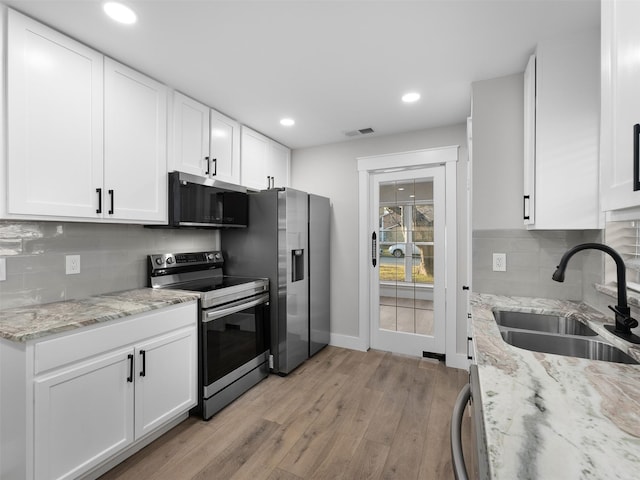 kitchen featuring appliances with stainless steel finishes, light wood-type flooring, light stone countertops, white cabinets, and sink