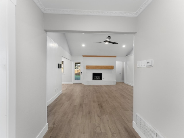 unfurnished living room with vaulted ceiling, ceiling fan, a fireplace, and light hardwood / wood-style flooring