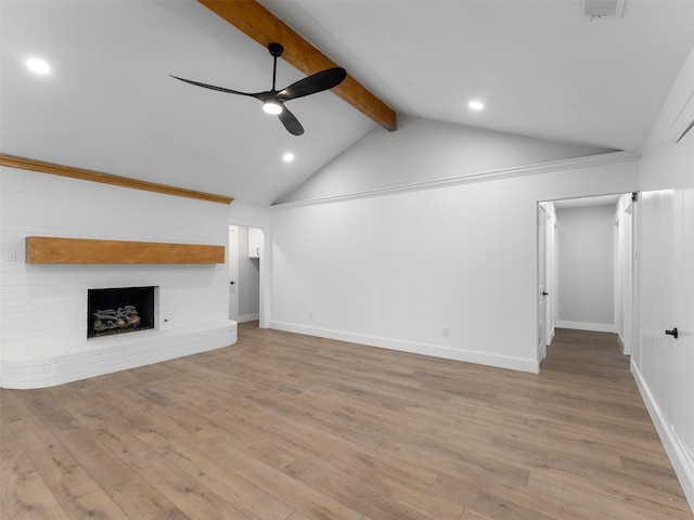 unfurnished living room featuring light hardwood / wood-style flooring, ceiling fan, a fireplace, and vaulted ceiling with beams