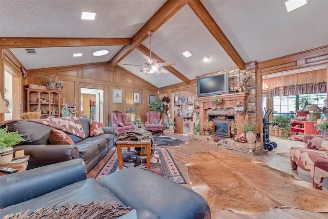 living room with hardwood / wood-style floors, wooden walls, vaulted ceiling with beams, ceiling fan, and a textured ceiling