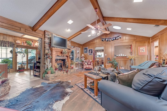 living room with vaulted ceiling with beams, a fireplace, light hardwood / wood-style floors, a textured ceiling, and wood walls