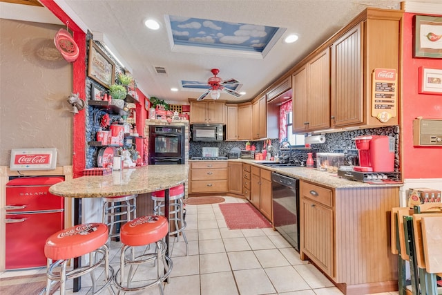 kitchen with a kitchen bar, sink, decorative backsplash, and black appliances