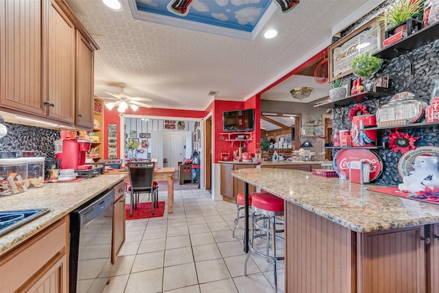 kitchen featuring light tile patterned flooring, tasteful backsplash, black dishwasher, a breakfast bar area, and a textured ceiling