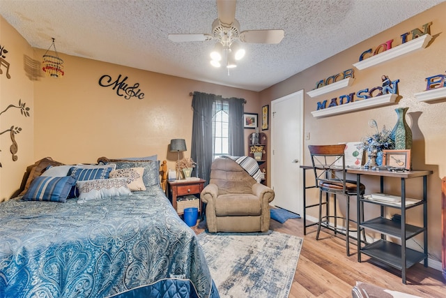 bedroom featuring ceiling fan, hardwood / wood-style floors, and a textured ceiling