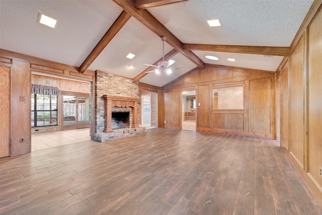 226 Meadowlark Ln, Duncanville, TX 75137 - unfurnished living room with vaulted ceiling with beams, wood walls, wood finished floors, a brick fireplace, and ceiling fan