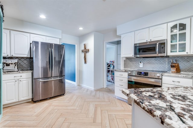 kitchen featuring light parquet floors, stainless steel appliances, white cabinets, and light stone counters