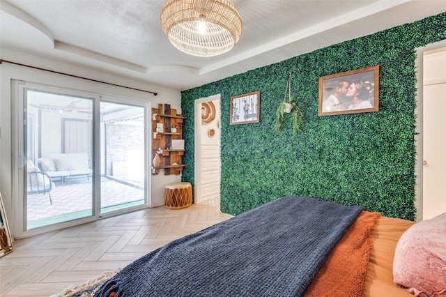 bedroom featuring parquet flooring, access to exterior, and a tray ceiling