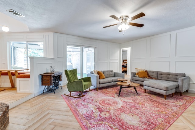 living room featuring a textured ceiling, light parquet floors, and ceiling fan