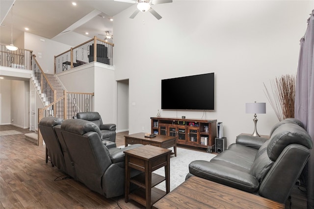 living room featuring ceiling fan, hardwood / wood-style floors, and a towering ceiling