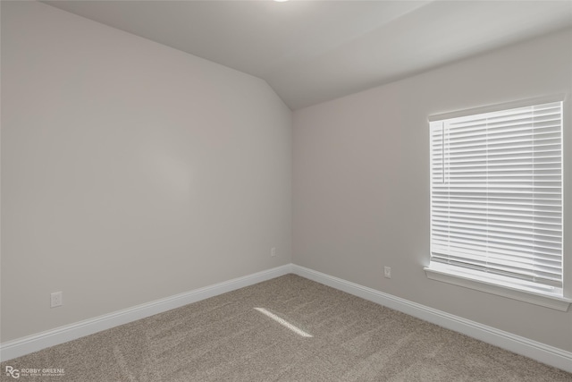 carpeted empty room with lofted ceiling