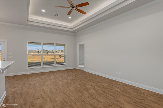 unfurnished room with a towering ceiling, ornamental molding, a raised ceiling, ceiling fan, and light hardwood / wood-style flooring